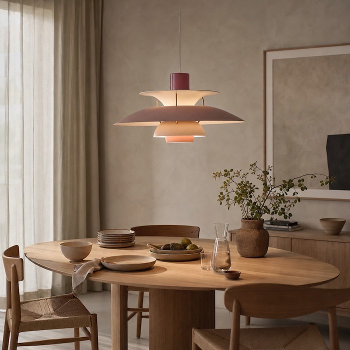 Gemütlicher, minimalistischer Essbereich mit mehrschichtiger Metallpendelleuchte, Gipswand, Holz, Leinen und Keramik.