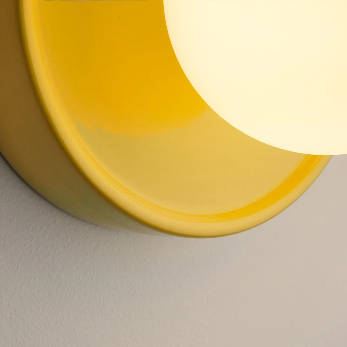 Leuchtende Glaskugel und gelber Keramiksockel im Detail