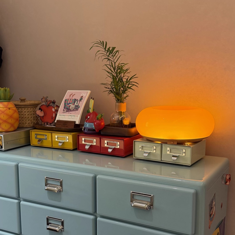Kundenfoto der eingeschalteten Donut-Tischleuchte auf einer Kommode