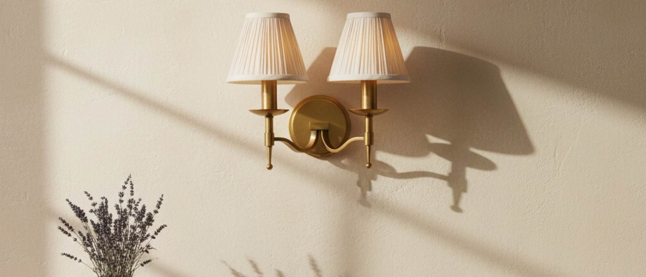 Tela curved-arm brass wall sconce with fabric shades in sunlight
