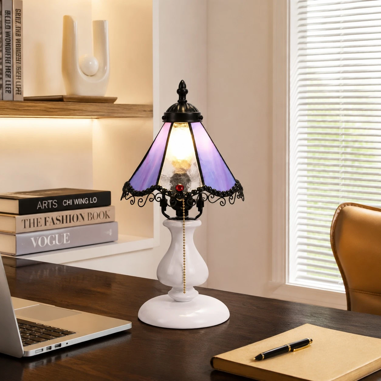 Gradient purple stained glass table lamp on a desk beside books and a laptop