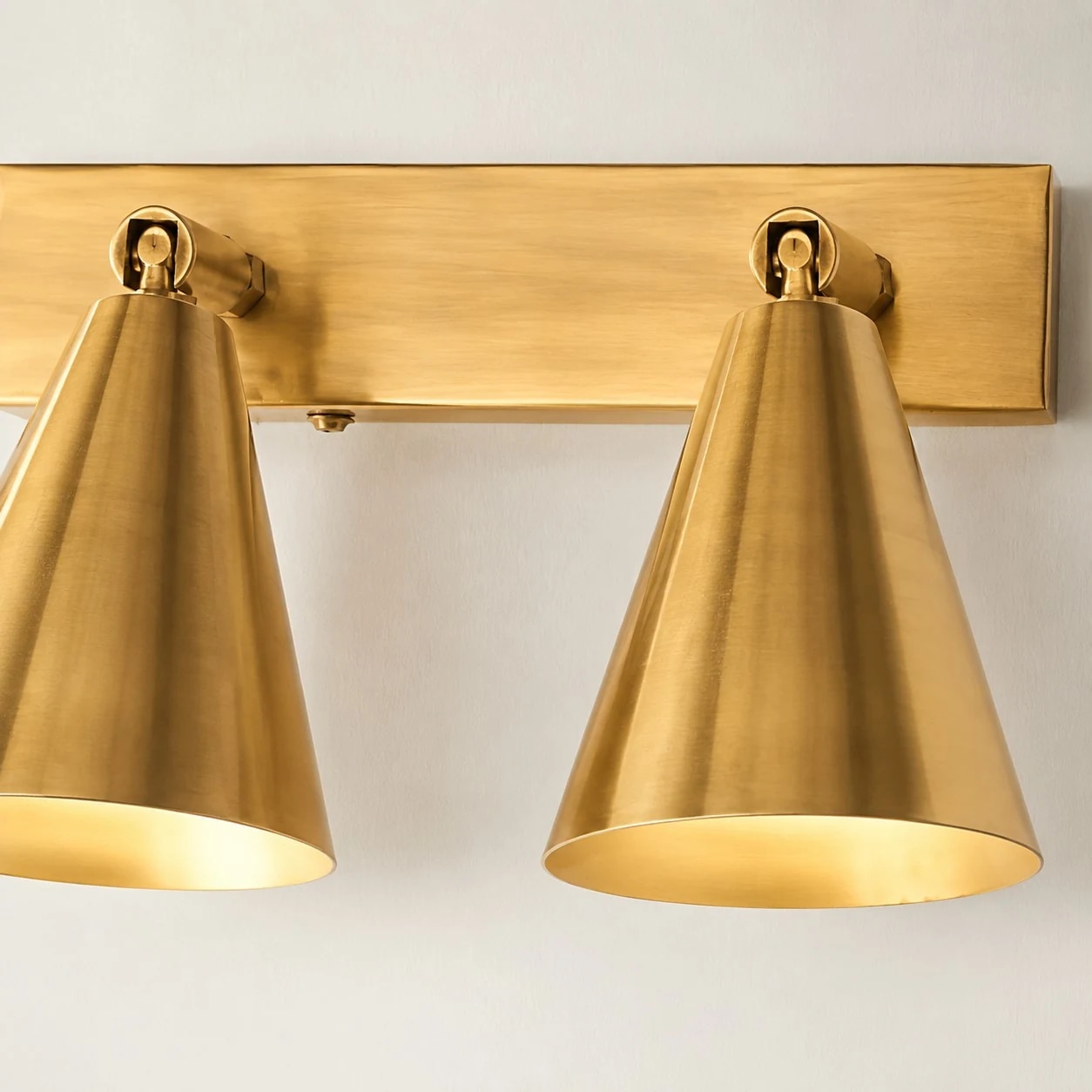 Close view of two brass adjustable cone shades with warm light