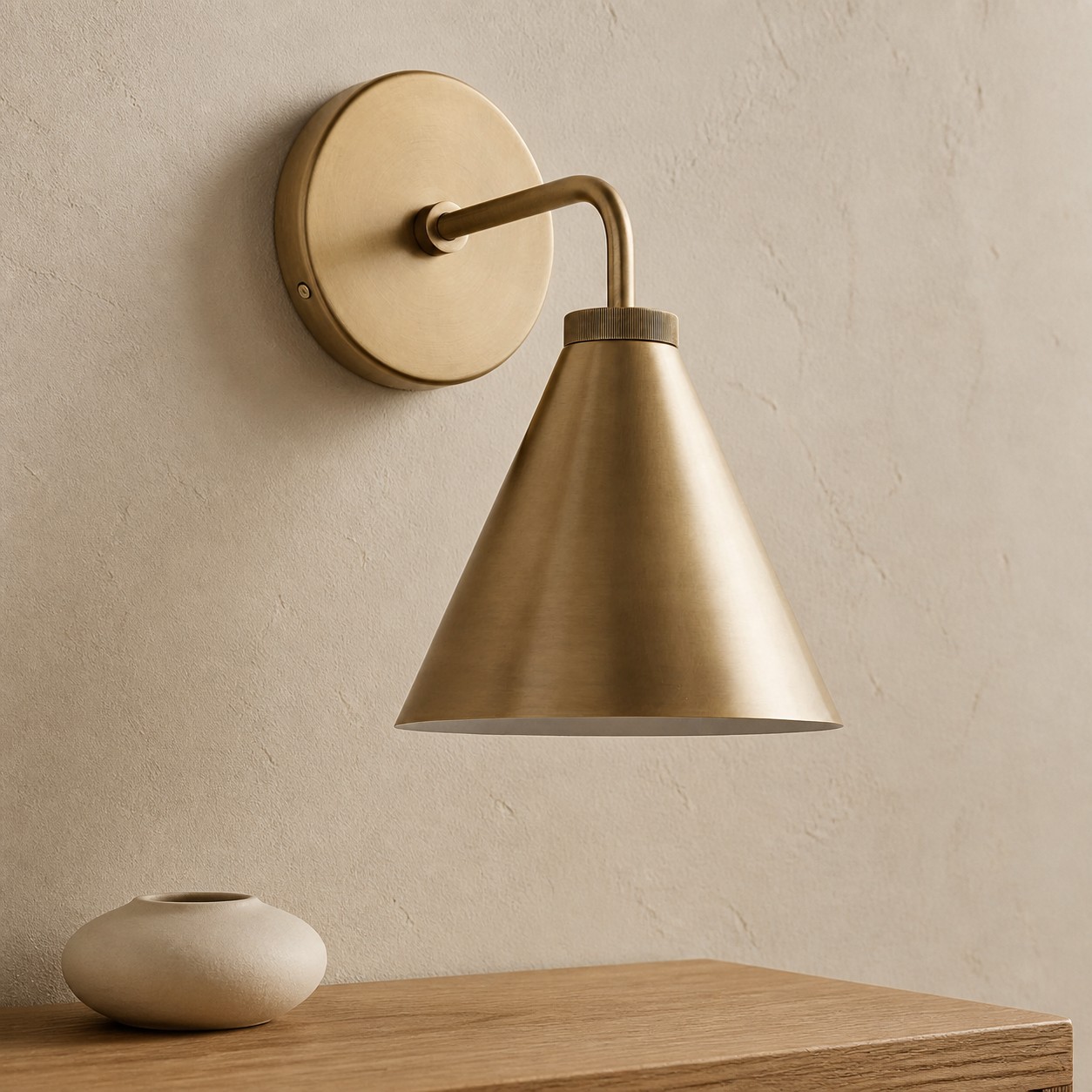 Tumbled brass Korvi wall lamp beside a nightstand