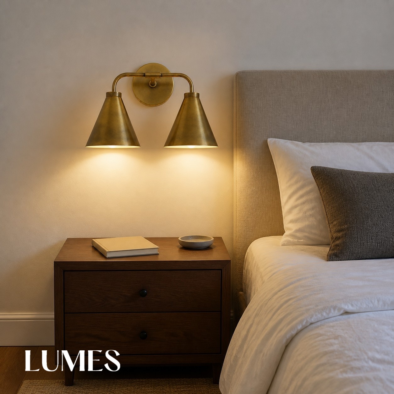 Dual head brass Korvi wall lamp above a bedroom nightstand