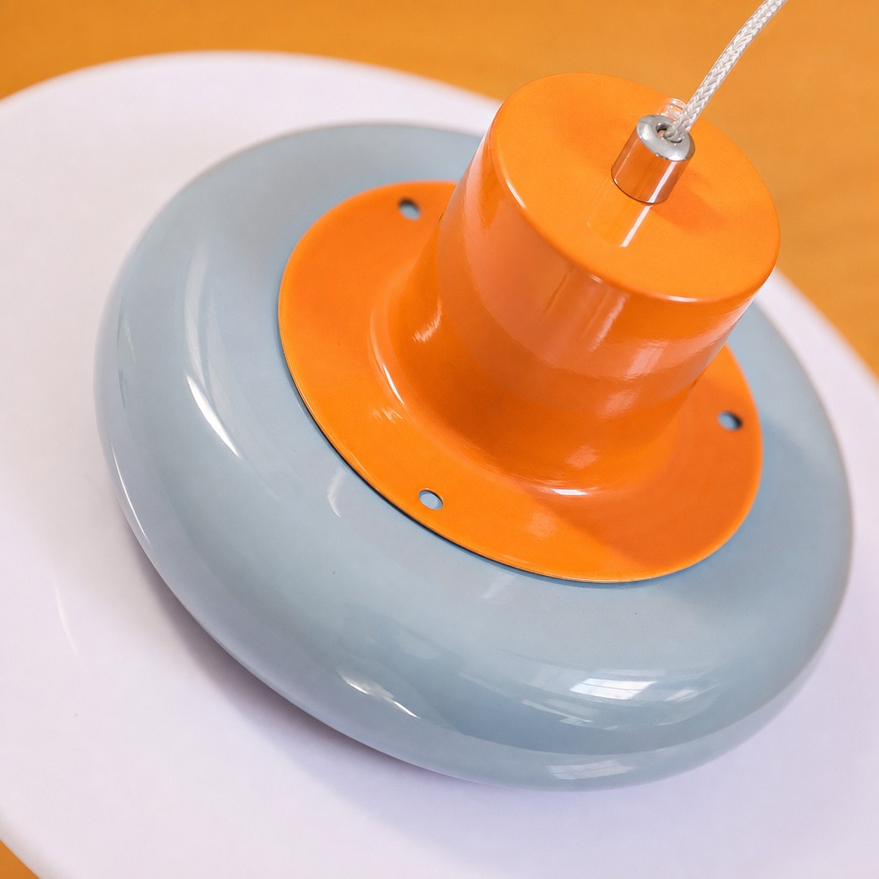 Close-up detail of glossy sea salt blue pendant shade, orange accent, and opal glass